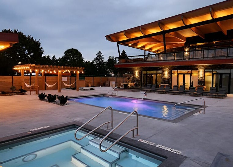 Illuminated pools and cozy hammocks at Wave Nordic Spa, Mount Elgin, Ontario, CA under twilight sky.