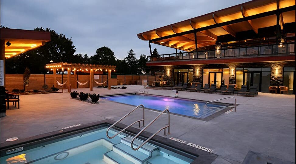 Illuminated pools and cozy hammocks at Wave Nordic Spa, Mount Elgin, Ontario, CA under twilight sky.