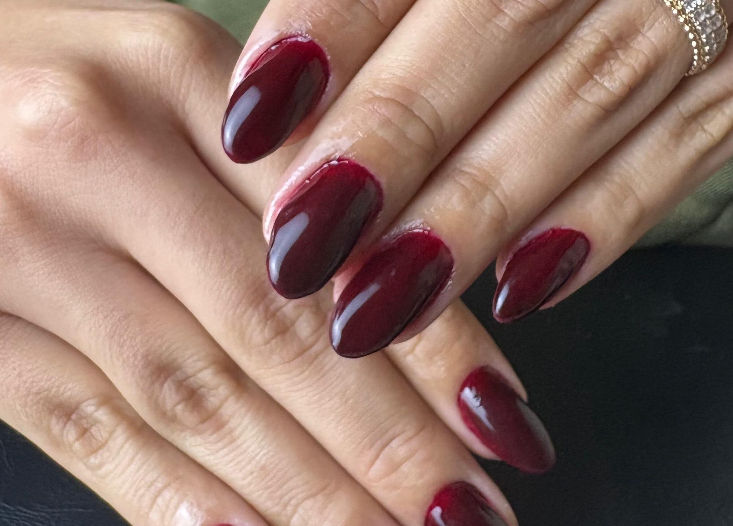 Manicure sofisticada em Studio Maira Gomes, Fafe, Braga, PT com esmalte vermelho escuro e acabamento brilhante.