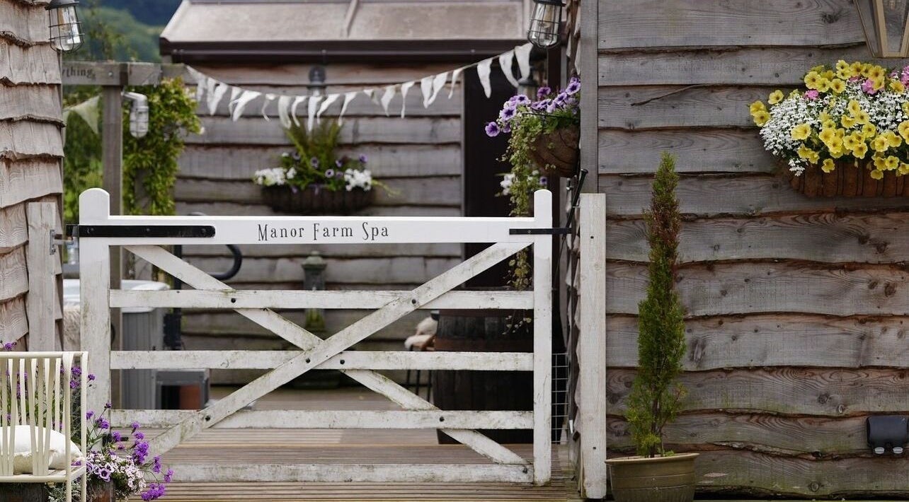 Entrance gate at Manor Farm Spa - Wellness Lounge in Thorpe Audlin, England, GB with flowers and rustic decor.