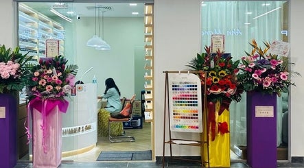 Entrance of Shimmer & Shine at Hougang Rivercourt, Rivercourt, SG, adorned with vibrant floral displays.