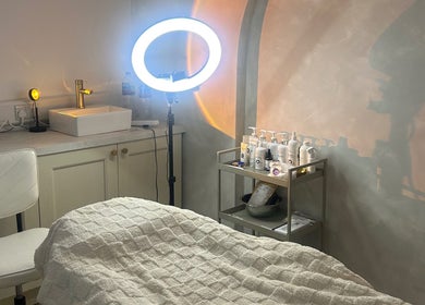 Relaxing treatment room at Skin Solutions Clinic, Middleton, England, GB with warm lighting and skincare products.