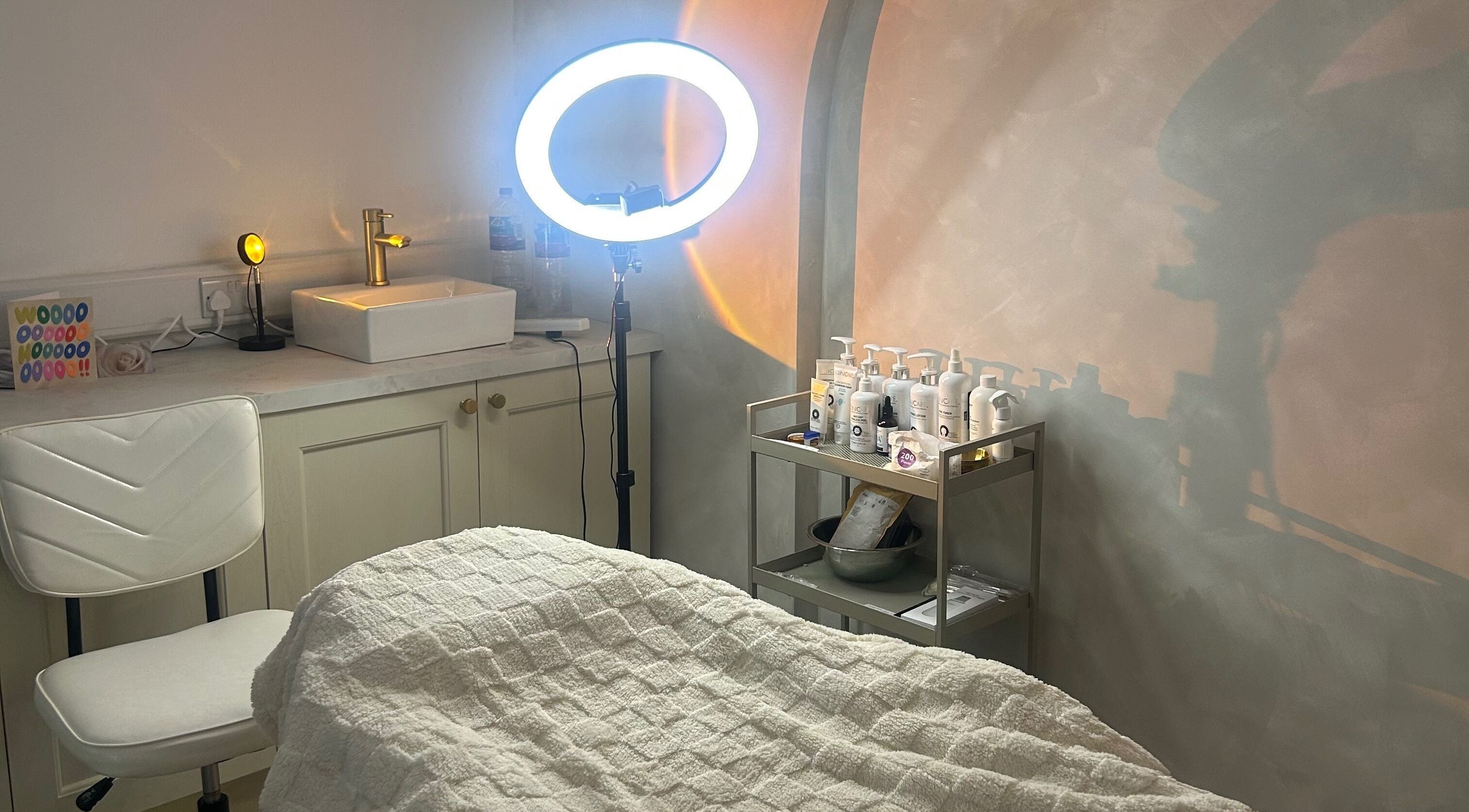 Relaxing treatment room at Skin Solutions Clinic, Middleton, England, GB with warm lighting and skincare products.