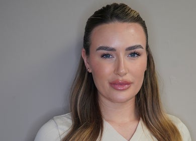 Professional beautician at Skin Solutions Clinic, Middleton, England, GB with flawless makeup and sleek hairstyle.