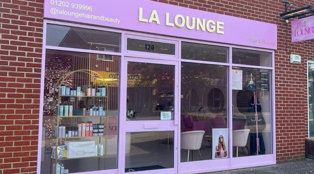 Hairby Issy Howard in Ferndown, England, GB. Stylish salon facade with purple signage and beauty products displayed.