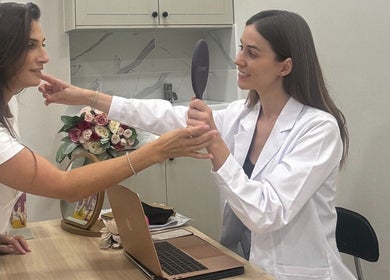 Consultation at InStudio Aesthetics, London, England, GB with a smiling client and practitioner using a mirror.