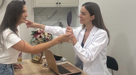 Consultation at InStudio Aesthetics, London, England, GB with a smiling client and practitioner using a mirror.