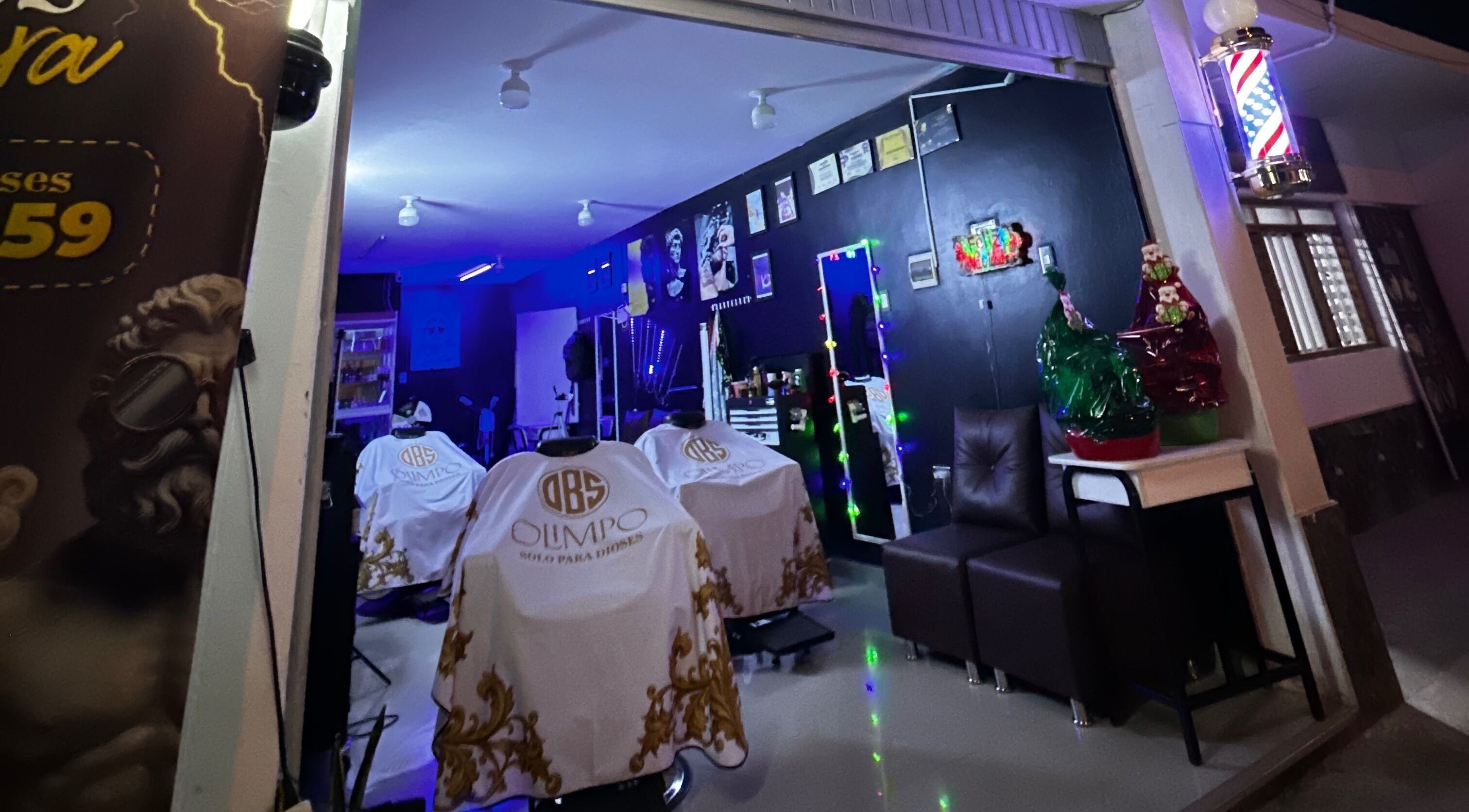 Interior del Olimpo barber studio en Chimbote, Áncash, PE, mostrando sillas de barbería blancas y decoración moderna.