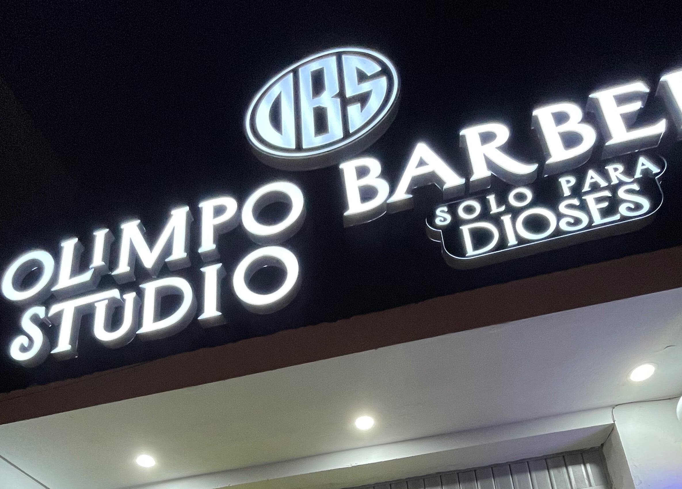 Letrero iluminado de Olimpo barber studio en Chimbote, Áncash, PE, destacando en la noche.