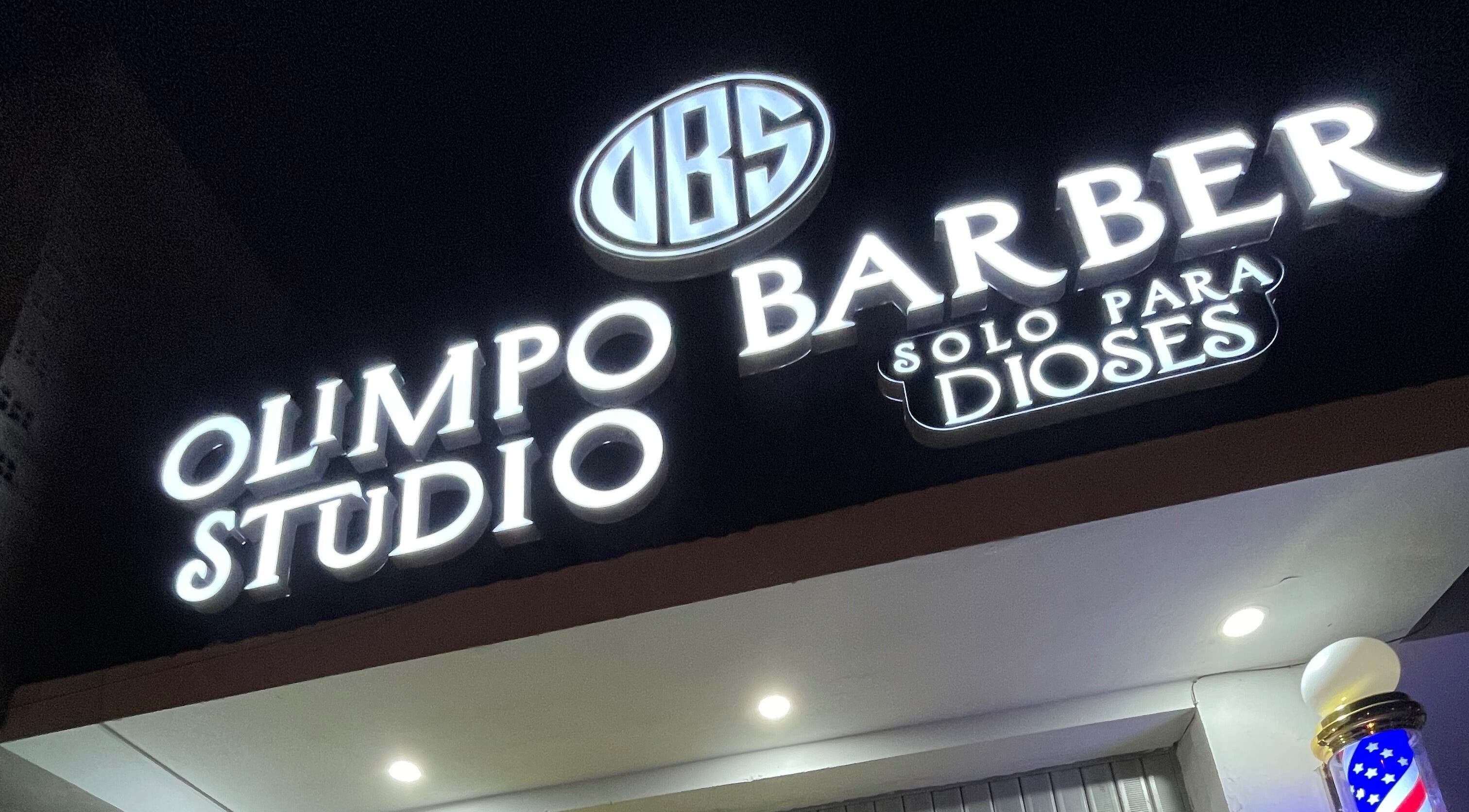 Letrero iluminado de Olimpo barber studio en Chimbote, Áncash, PE, destacando en la noche.