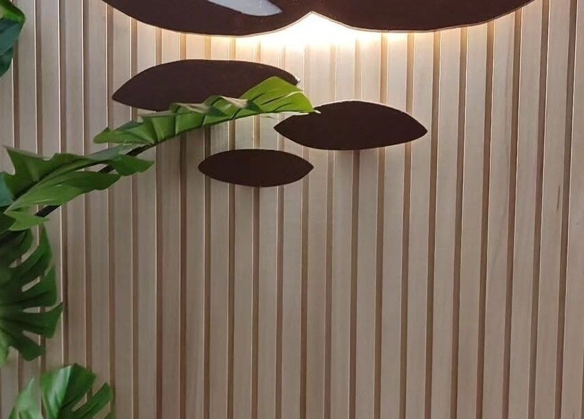 Decorazione artistica a Waiora Estetica & Benessere, Tuglie, Puglia, IT con foglie verdi su sfondo ligneo.