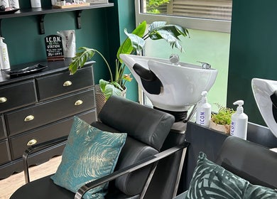 Chic hair washing stations at Asha The Hair Lounge in London, GB featuring modern black furnishings and lush plants.