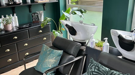 Chic hair washing stations at Asha The Hair Lounge in London, GB featuring modern black furnishings and lush plants.