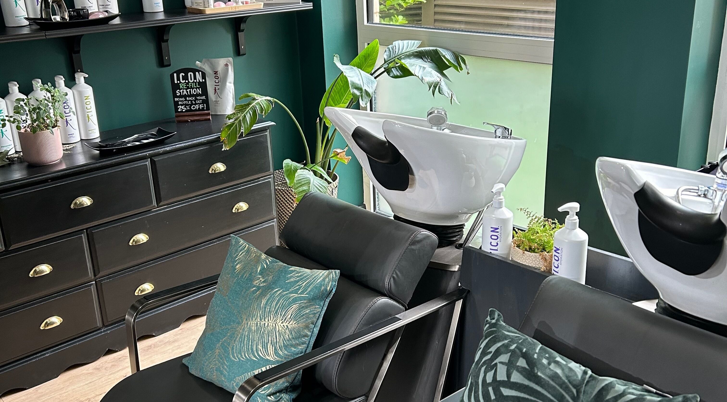 Chic hair washing stations at Asha The Hair Lounge in London, GB featuring modern black furnishings and lush plants.