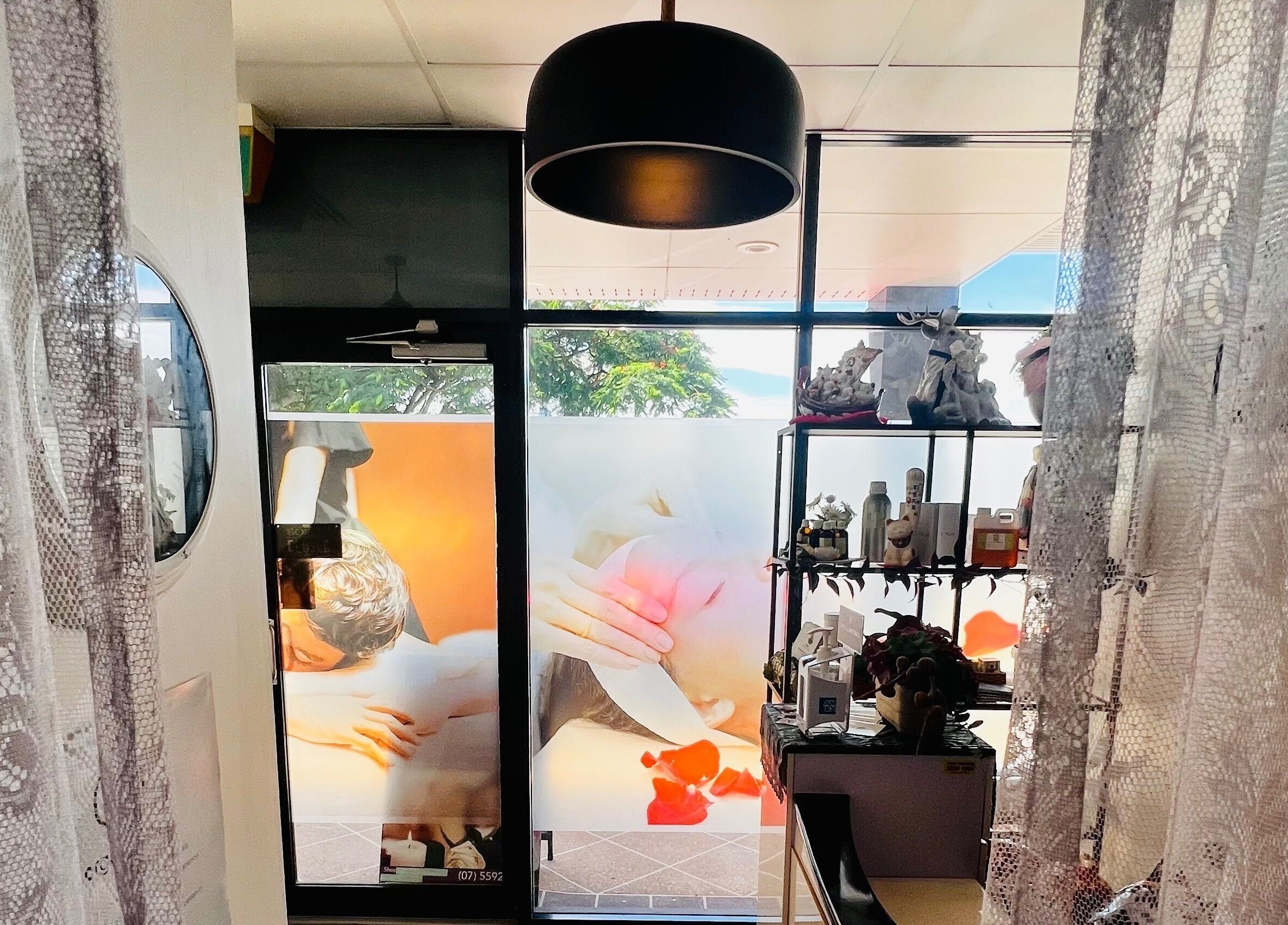 Interior of Flex Beauty and Aroma, Bundall, Queensland, AU. Decorative lace curtains and shelves with beauty products.