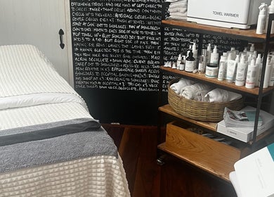 Treatment room at Glow by Daisy, Crabtree, England, GB with bed, towel warmer, and skincare products.