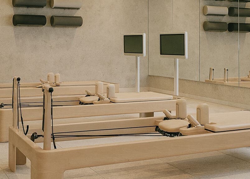 Pilates reformer room at Being | Fourways, Sandton, Gauteng, ZA, featuring wooden equipment and mirrored walls.