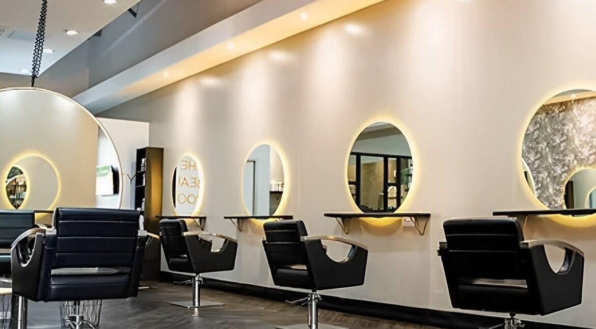 Modern salon interior at Hair by Toni Cooke, Peterborough, England, GB with sleek chairs and illuminated mirrors.