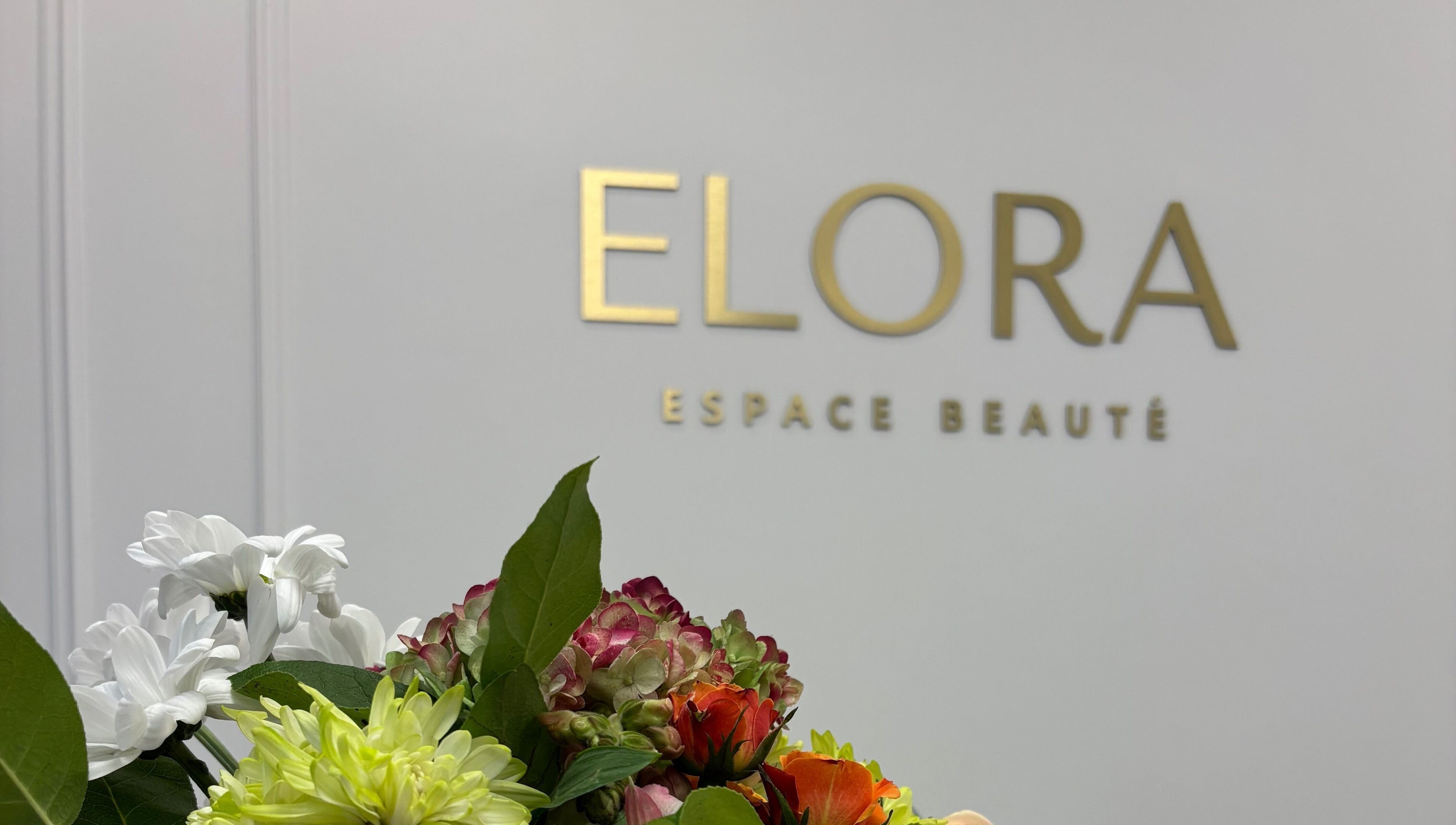 Un bouquet de fleurs devant le logo ELORA Laser à Laval, Québec, CA.