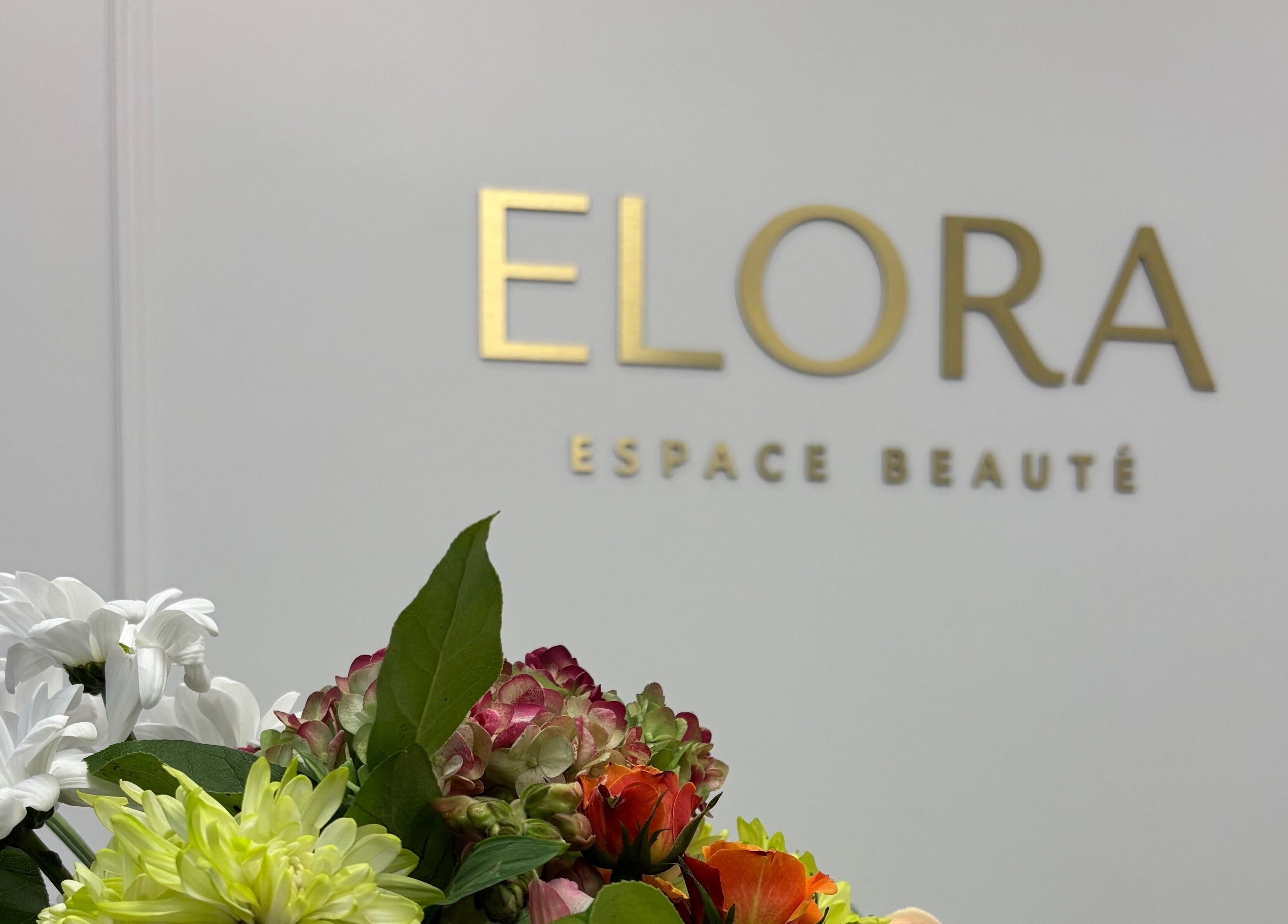 Un bouquet de fleurs devant le logo ELORA Laser à Laval, Québec, CA.