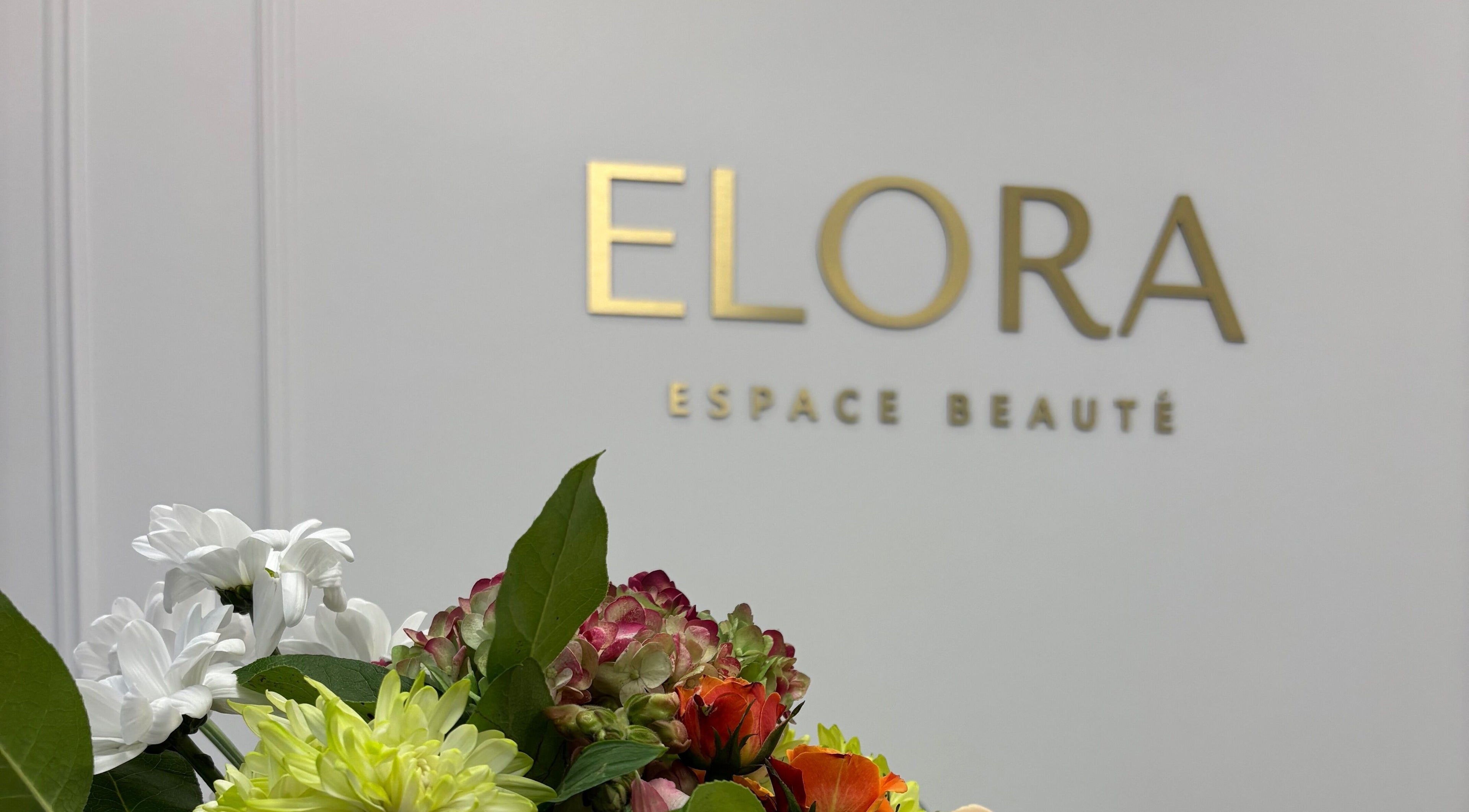 Un bouquet de fleurs devant le logo ELORA Laser à Laval, Québec, CA.