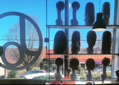 Stylish wigs on display at Jo Hair Studio Vancouver, Vancouver, British Columbia, CA, against a sunlit window.