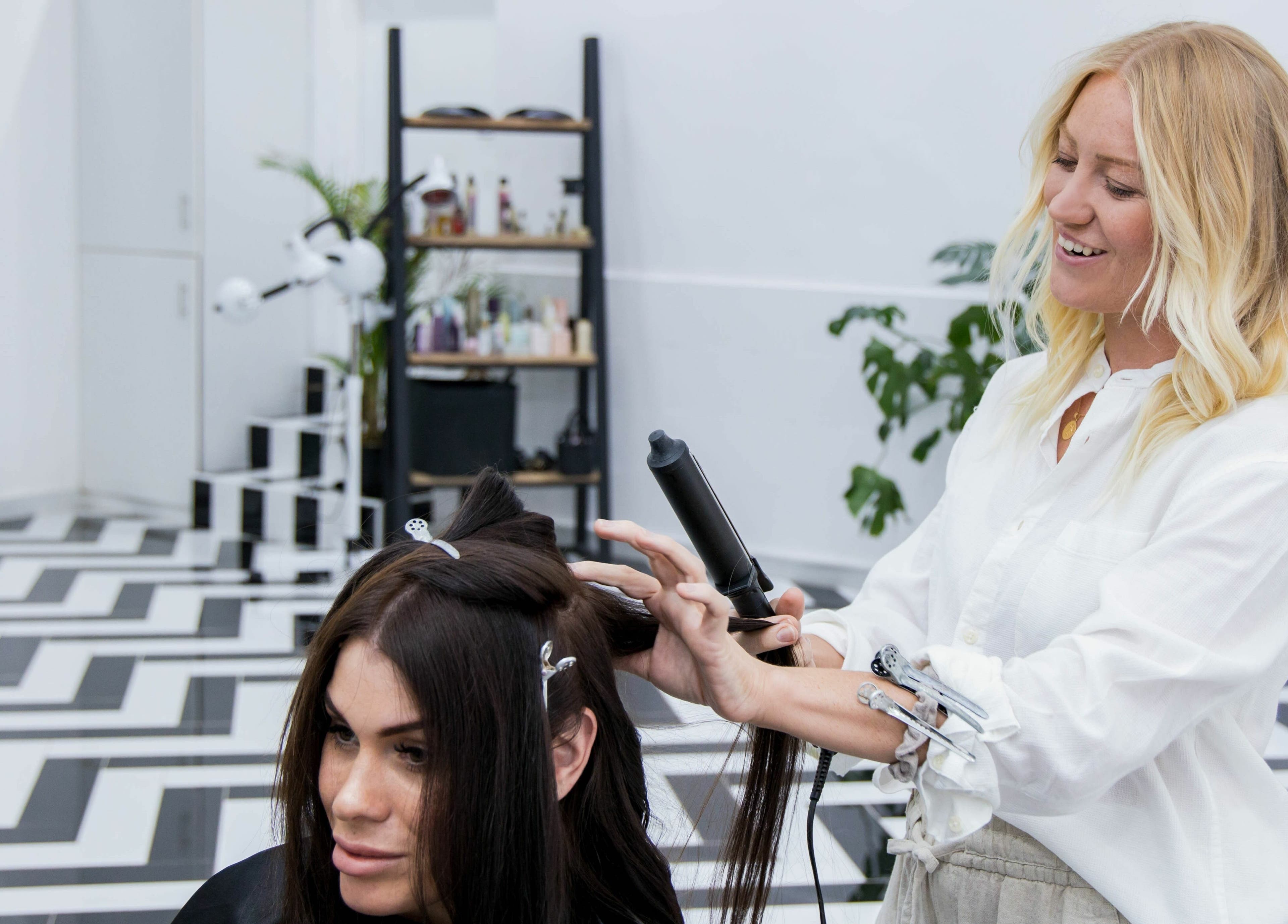 Hair stylist at Color Iconic Ladies Salon in Dubai, AE, curling a client's hair with precision and care.