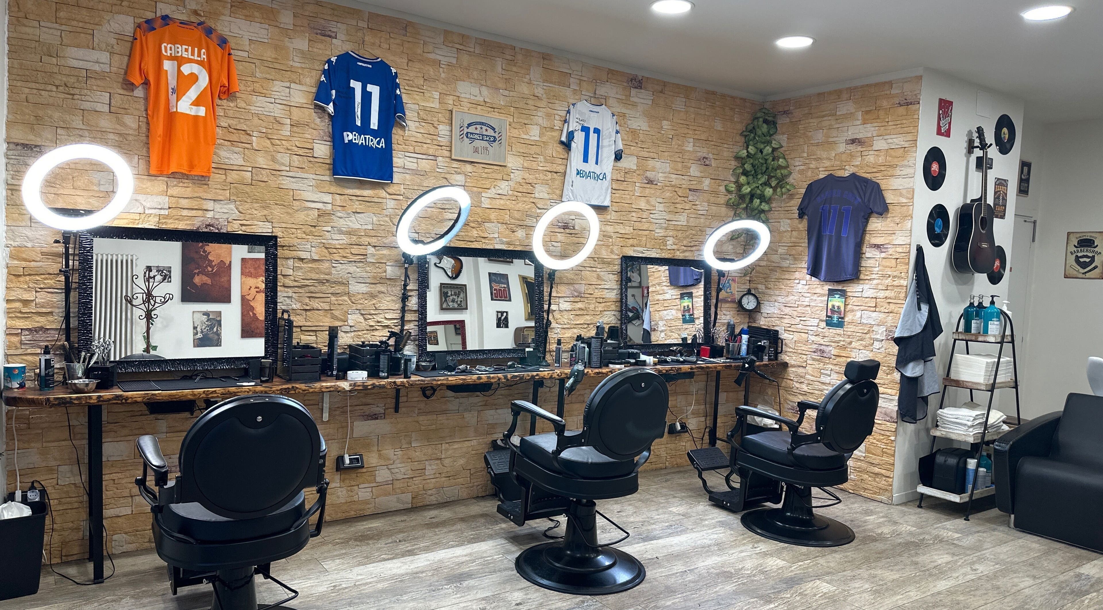 Interno moderno di Barber Crew 111 a Asti, Piemonte, IT con sedie e decorazioni uniche.