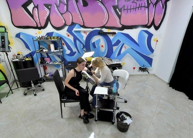Салон Piercing Hub в Івано-франківську. Майстер робить пірсинг, яскравий графіті інтер'єр.