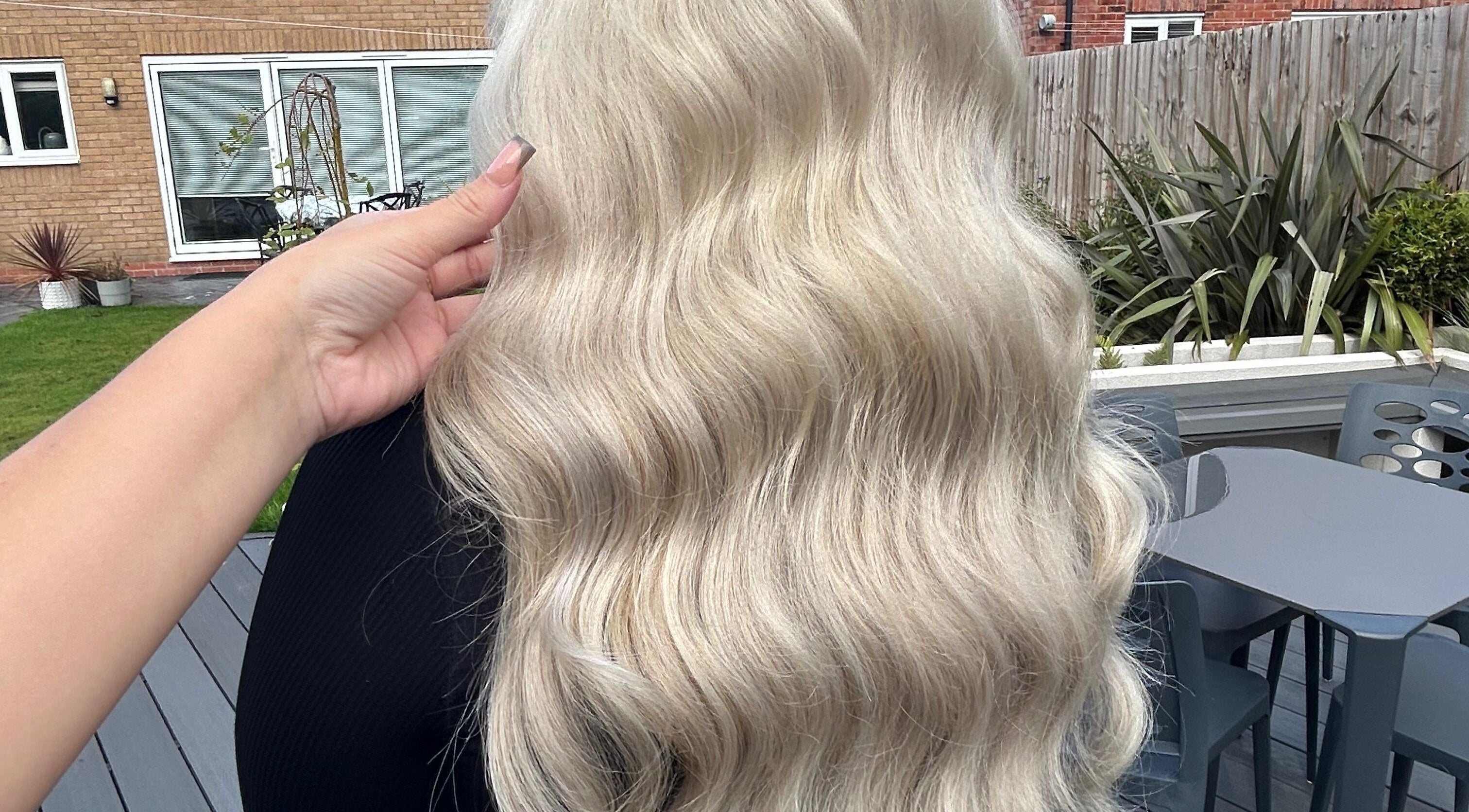 Blonde wavy hairstyle crafted by Hair By Mia in Stafford, England, GB, showcased in a lush garden.