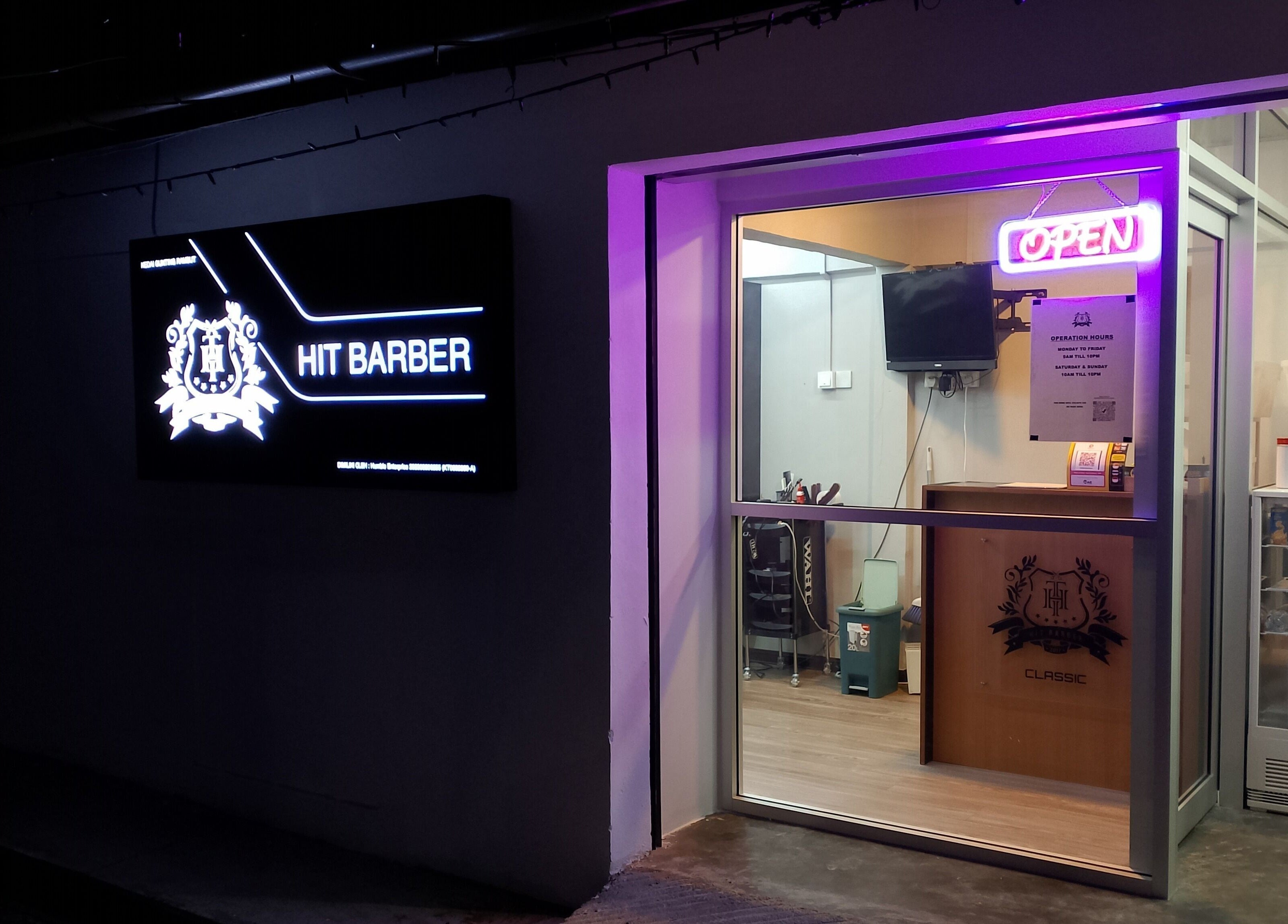 Entrance of Hit Barber Classic TTDI, Kuala Lumpur, showcasing neon signs and inviting interior.