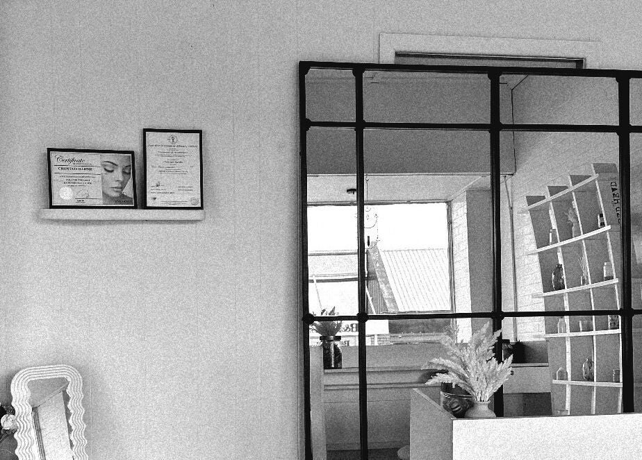 Elegant interior of Khai Beauty, Portland, NSW with decor and displayed certificates on a cozy wall shelf.