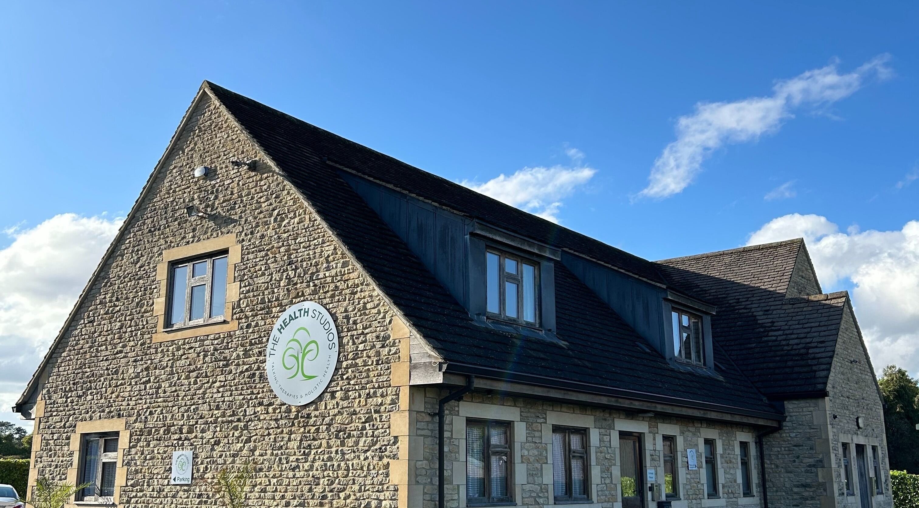 Christie Louise Massage venue in Cirencester, England. Charming stone building with clear blue sky backdrop.