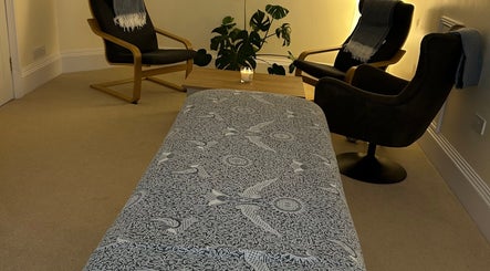 Relaxing massage room at Christie Louise Massage in Cirencester, England, GB with patterned table cover and cozy chairs.