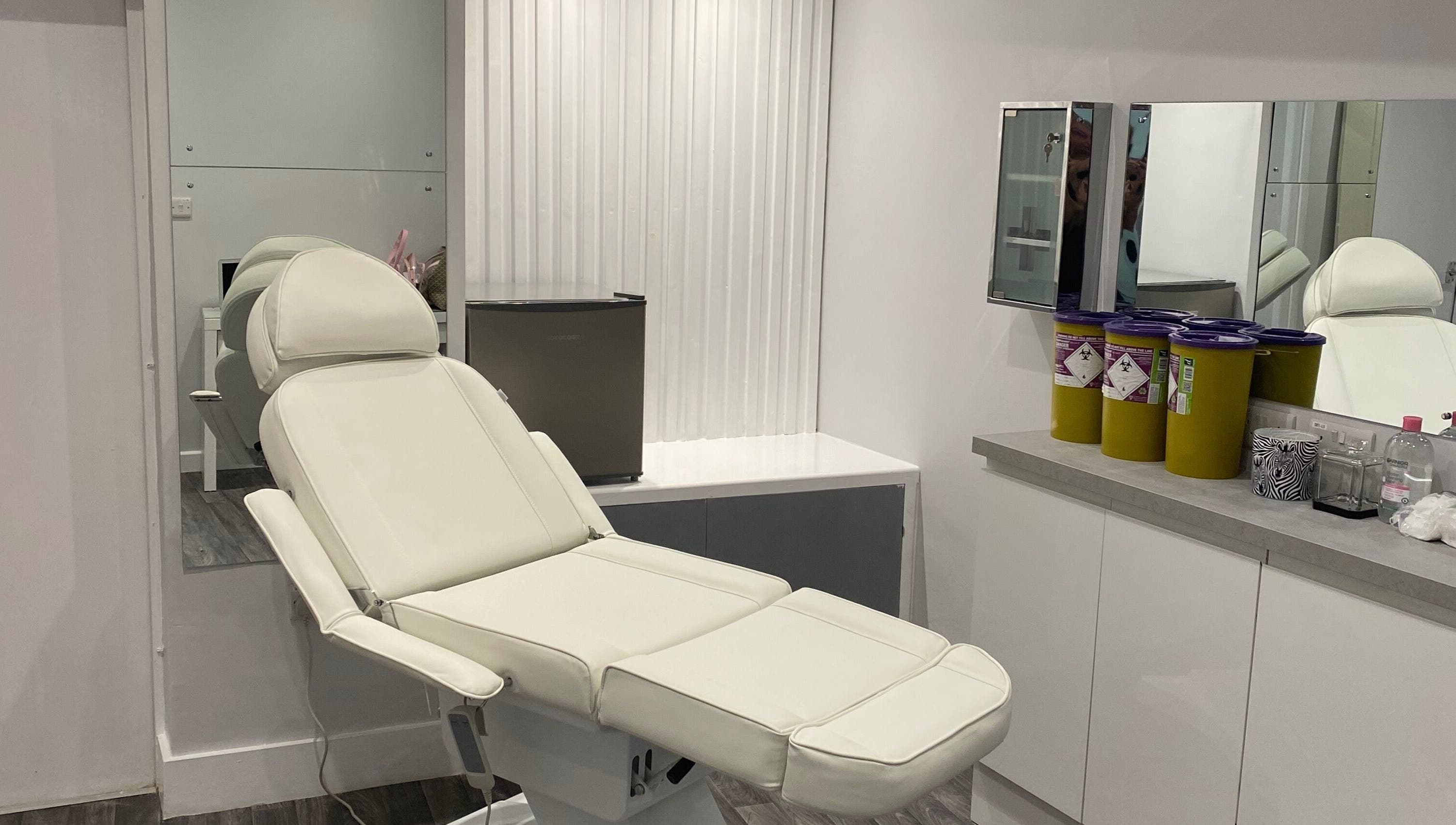 Modern treatment room at House of Boo, Petersfield, England with a sleek white chair and mirrors.