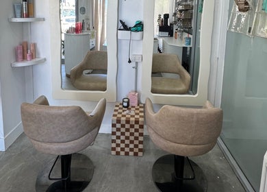Stylish salon chairs at Isla Hair, Maroochydore, Queensland, AU, showcasing two large mirrors and chic decor.