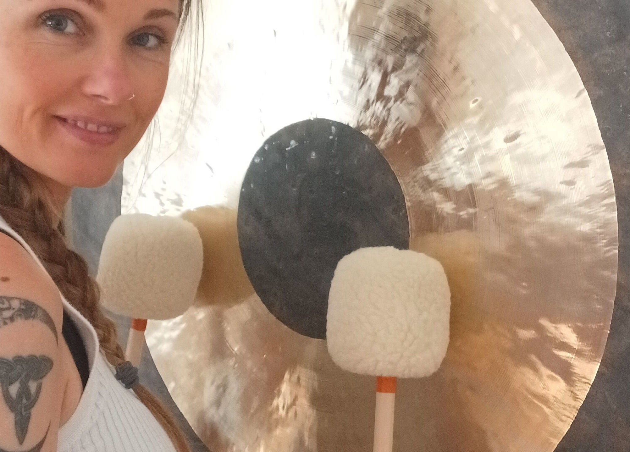 Woman with tattoo playing a gong at Kernow Serenity, Truro, England, GB.