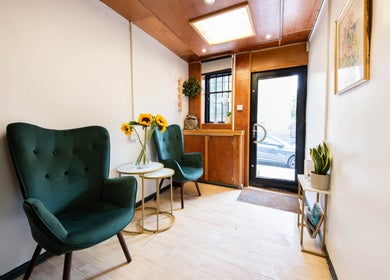 Inviting seating area at Glaysson Carvalho Hair Studio, London, England, GB with green chairs and sunflowers.