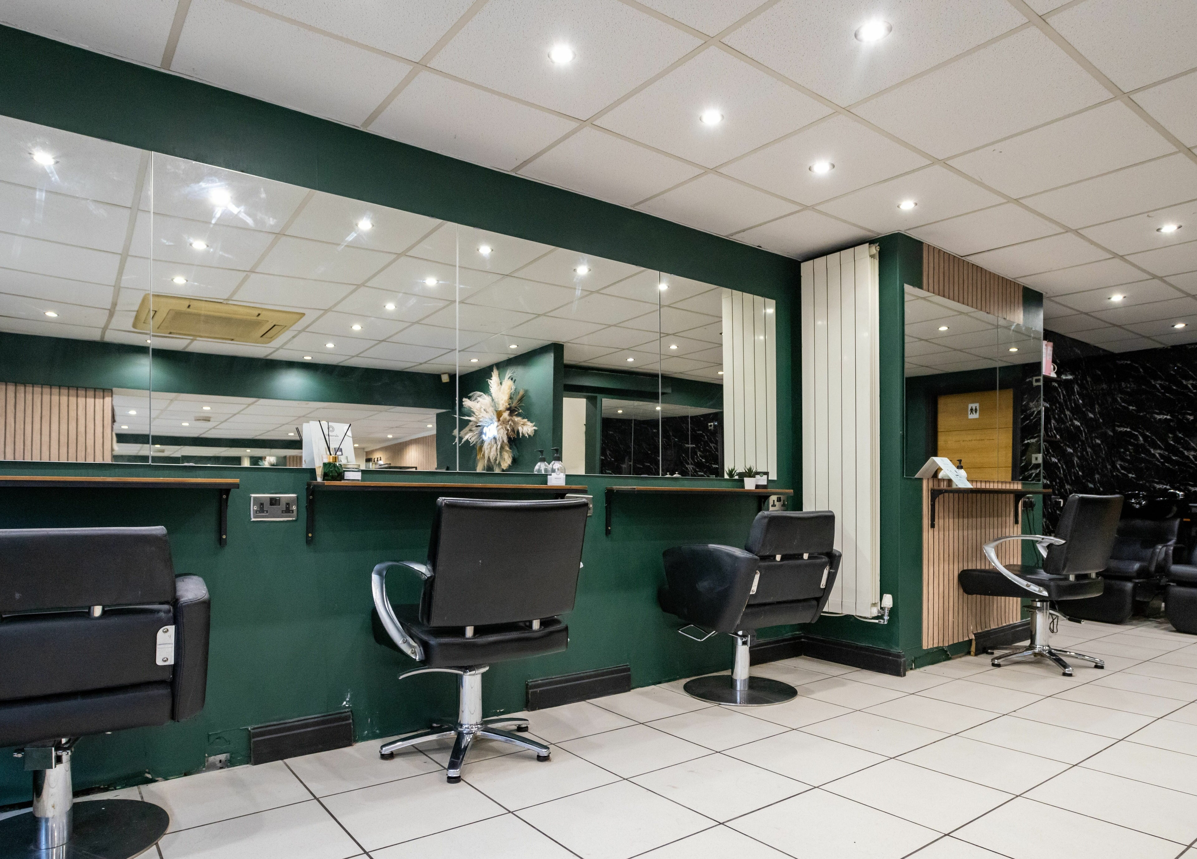 Chic salon interior at The House of Castelliś, Hyde, England, GB, featuring stylish black chairs and green accents.