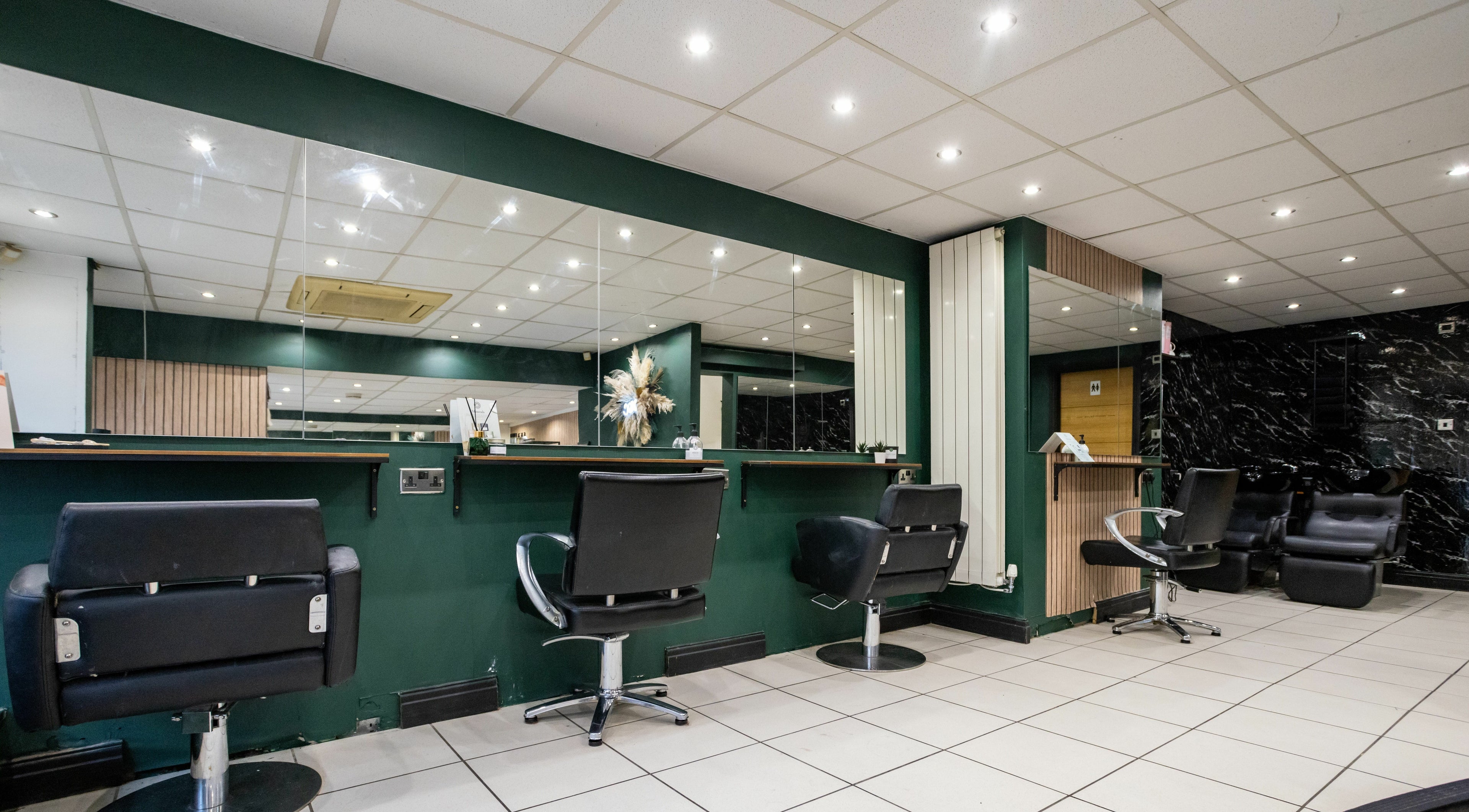 Chic salon interior at The House of Castelliś, Hyde, England, GB, featuring stylish black chairs and green accents.