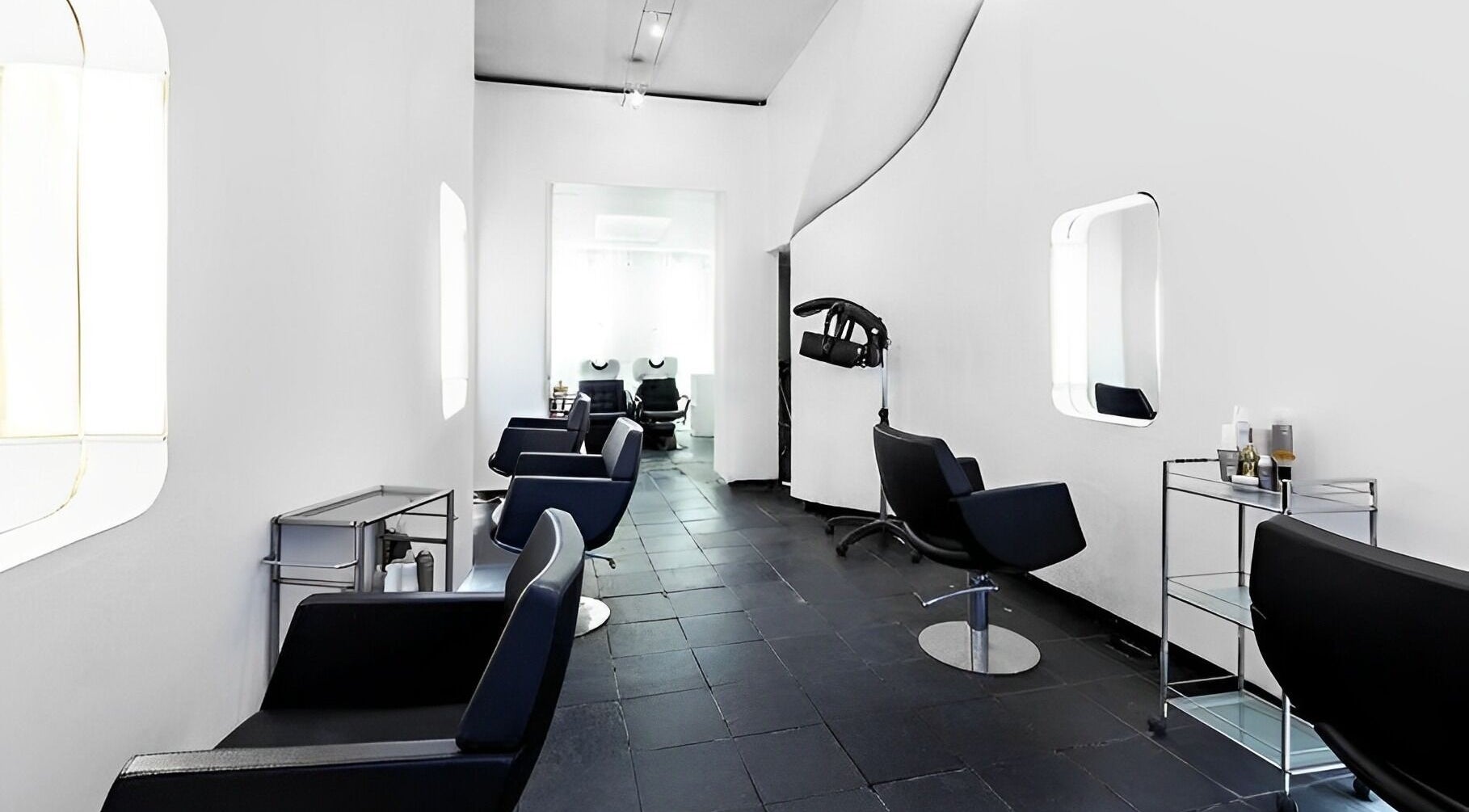 Sleek, modern salon interior at Ticro Hair, London, England, GB with chic black chairs and minimalist decor.