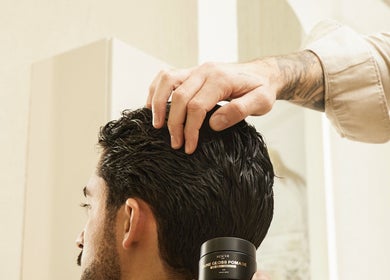Stylist applying pomade at Kochi Dubai Gents Salon, Dubai, Dubai, AE for a sleek hairstyle.