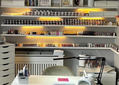 Cozy nail salon setup at Pampered Beauty, Elphinstone, Scotland, GB with shelves of nail products.