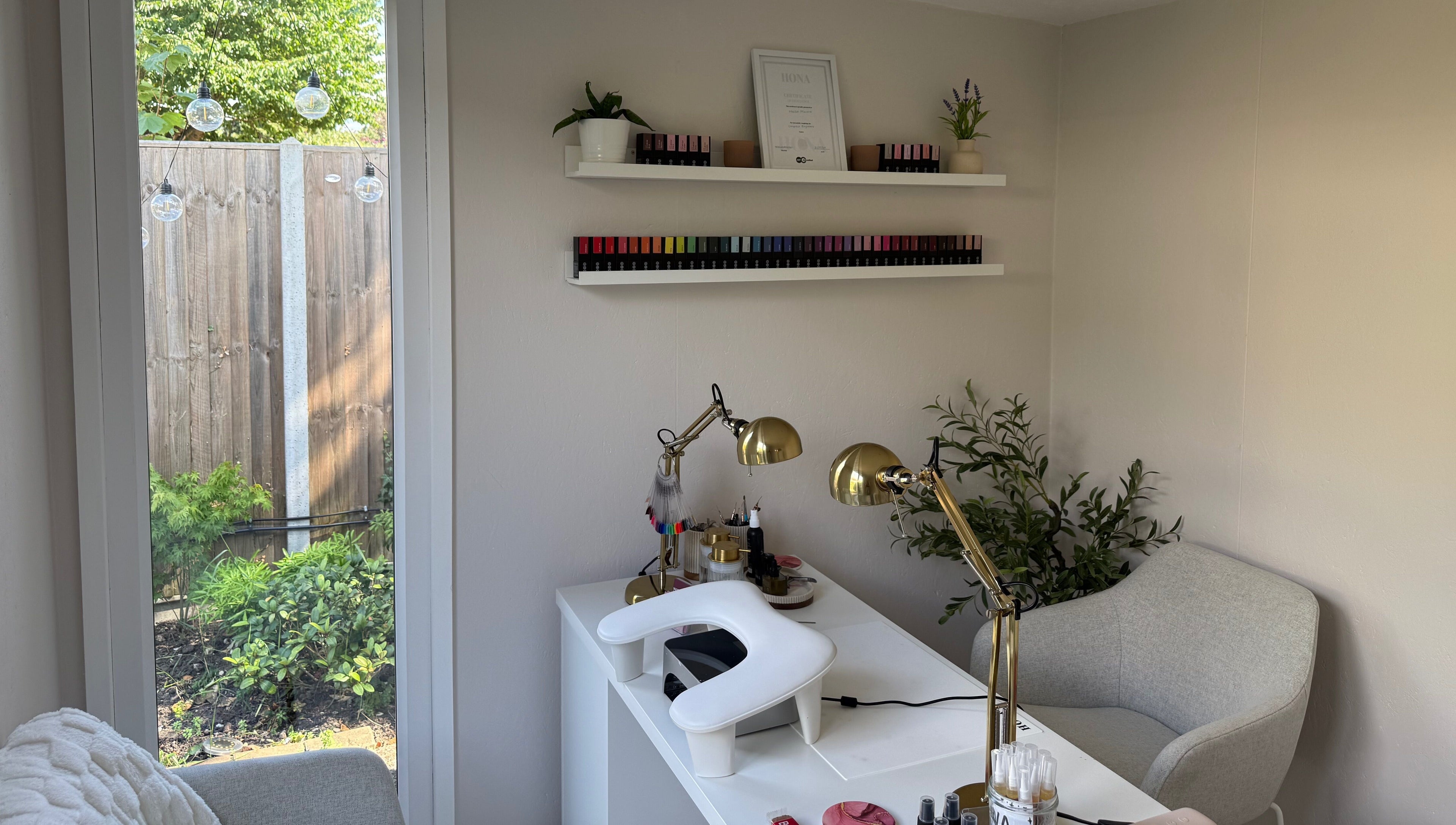 Elegant nail salon setup at Manis By Mais, Epsom, England, GB with nail polishes and greenery.