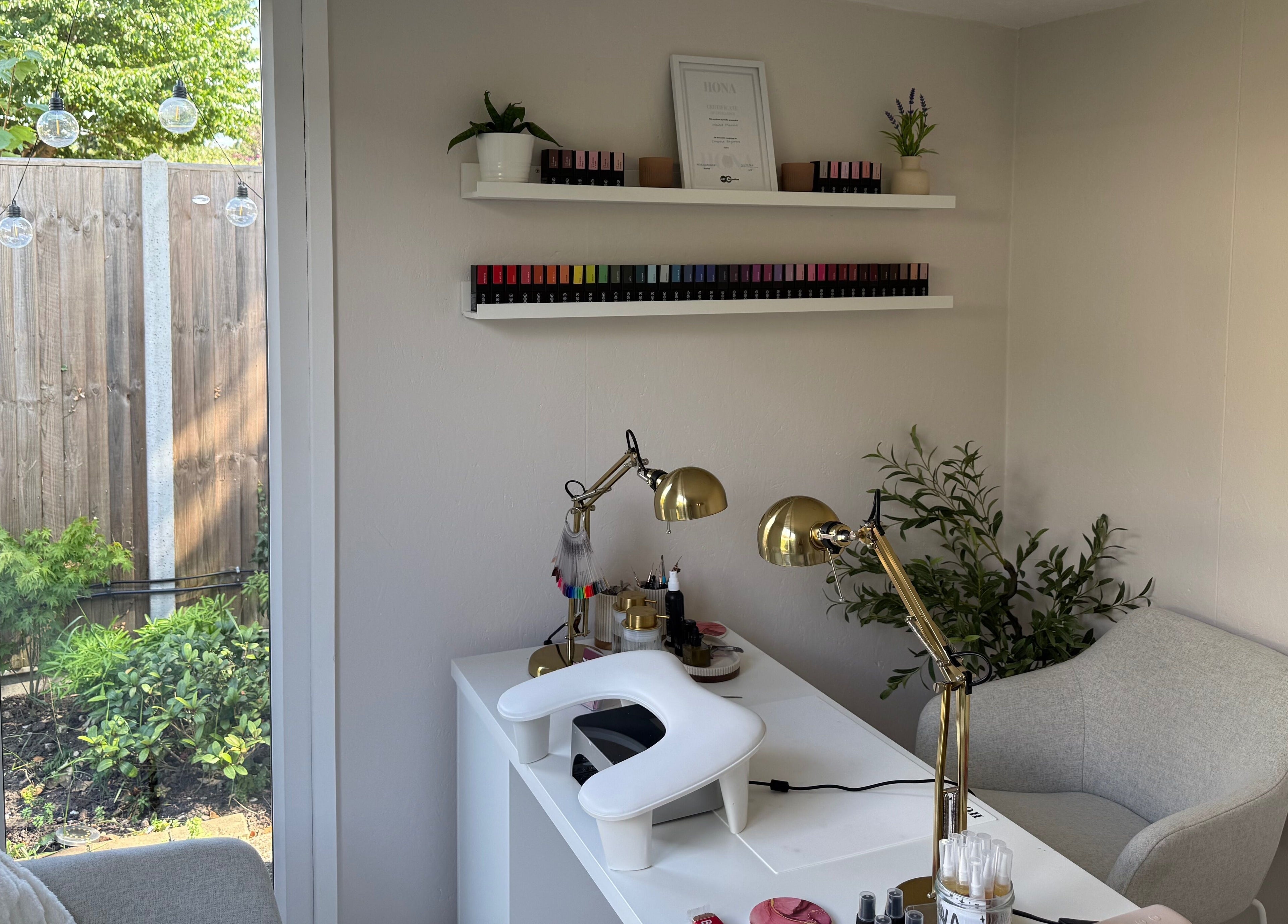 Elegant nail salon setup at Manis By Mais, Epsom, England, GB with nail polishes and greenery.