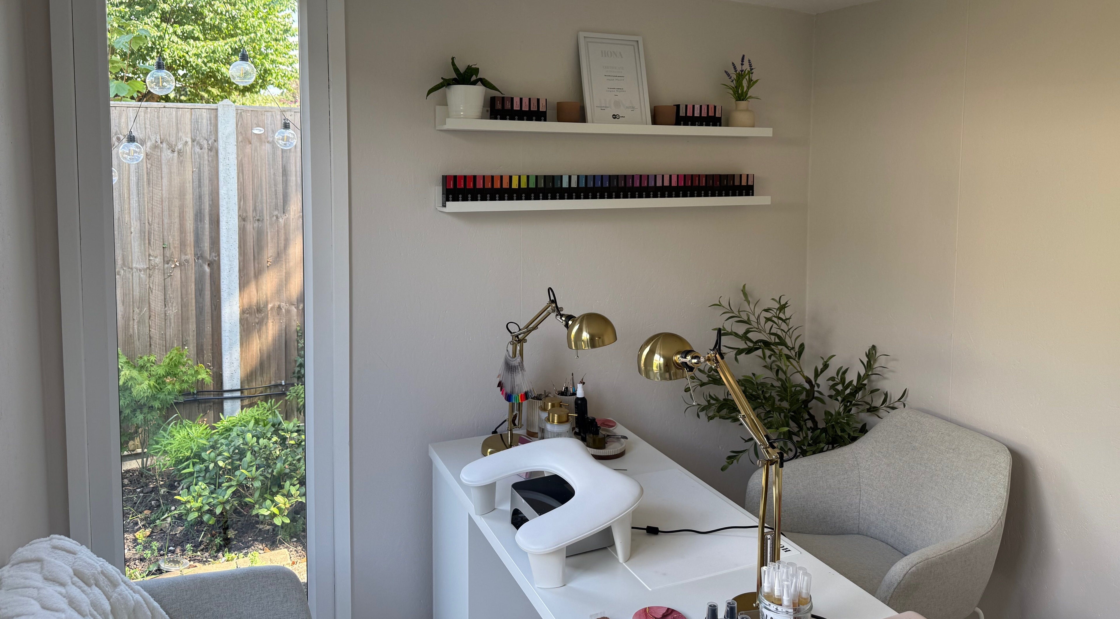 Elegant nail salon setup at Manis By Mais, Epsom, England, GB with nail polishes and greenery.