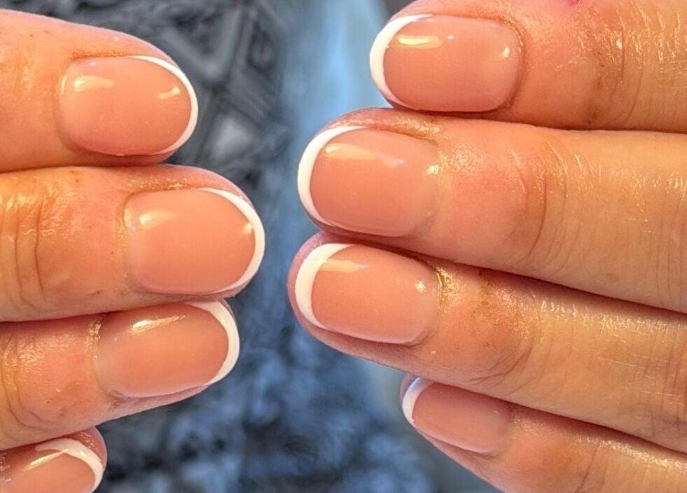 Elegant French manicure at Manis By Mais in Epsom, England, GB, showcasing glossy pink nails with white tips.