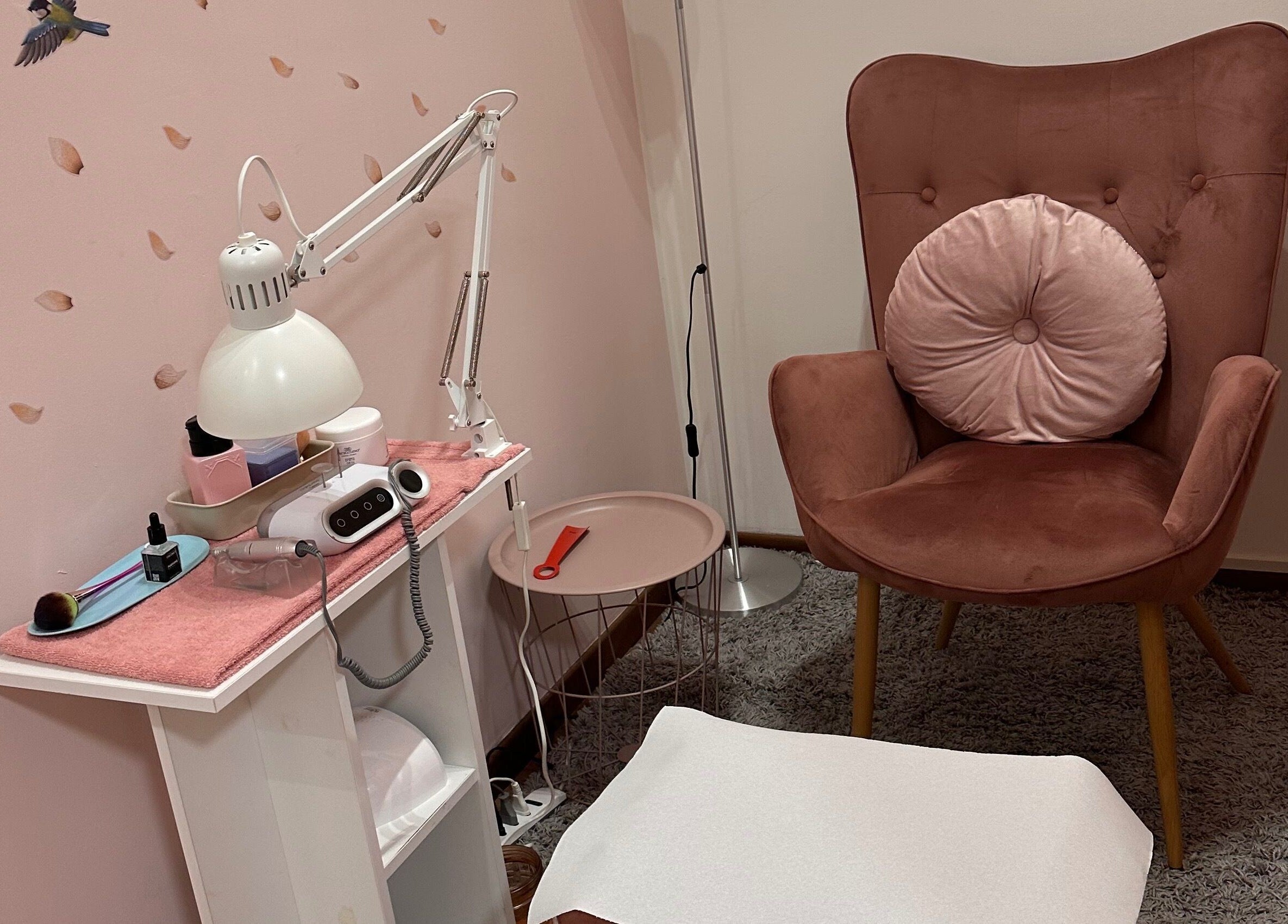 Area relax di Beauty and Nails di Ariano Ylenia a Pusiano, Lombardia, IT. Poltrona rosa elegante e lampada.