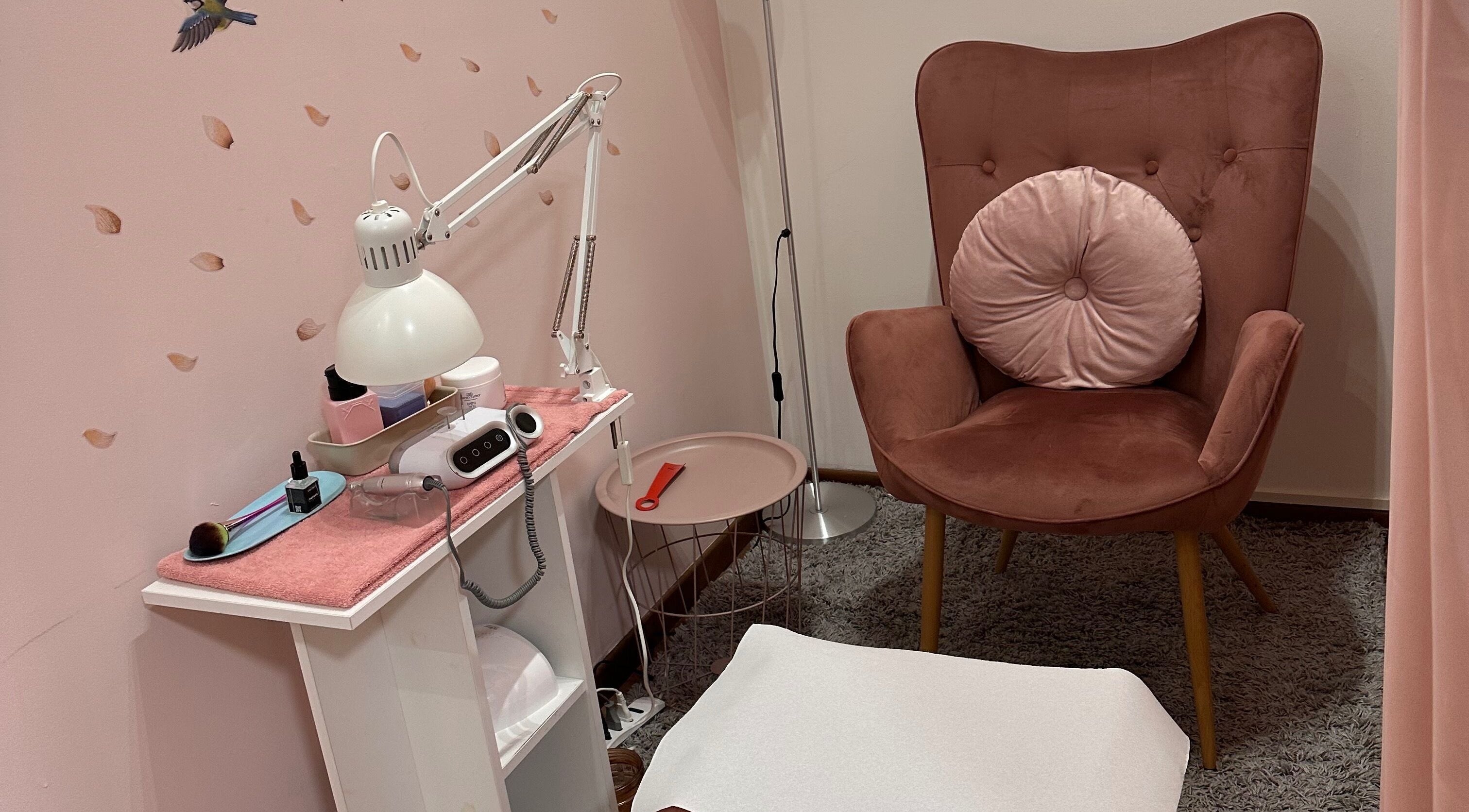 Area relax di Beauty and Nails di Ariano Ylenia a Pusiano, Lombardia, IT. Poltrona rosa elegante e lampada.