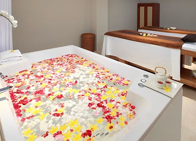Petal-filled spa bath at Visala Spa The Bandha, Bali, Bali, ID with serene massage tables nearby.